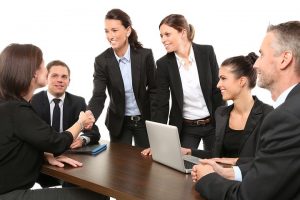 Group of business people around a desk congratulate an individual